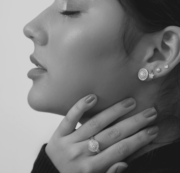 Woman wearing diamond earrings and ring.